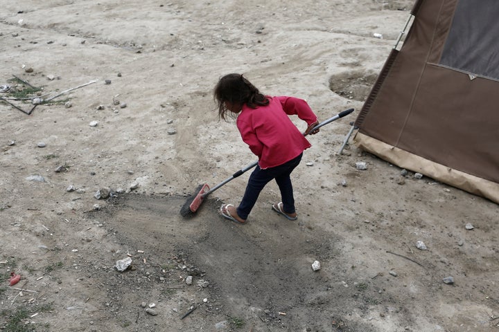 A small girl cleans up the area outside her tent in a makeshift refugee camp on the Greek-Macedonian border, on May 19, 2016.