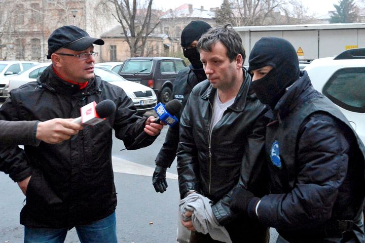 Marcel Lazar Lehel is escorted by masked policemen in Bucharest, after being arrested in Arad on January 22, 2014.
