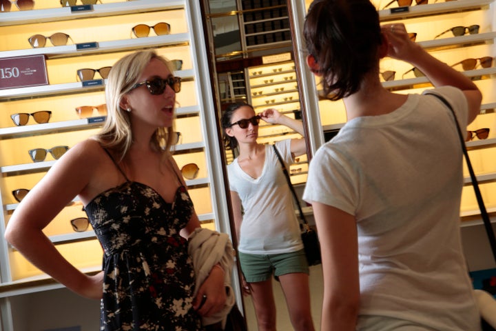 Two shoppers try on glasses at Warby Parker.