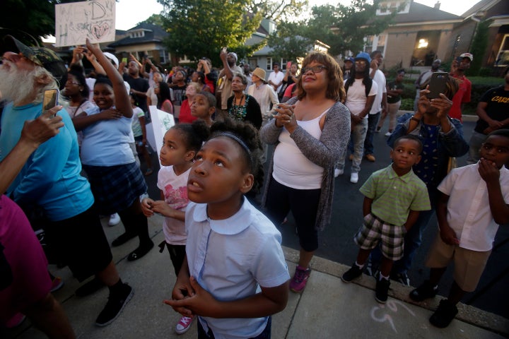 People watch as Father Pfleger of St. Sabina Church hangs the American flag upside down on the flag pole outside of his church during a protest for the recent uptick in homicides across the city on Aug. 31 in Chicago. Chicago has seen over 80 people killed and over 400 people shot and wounded during the month of August, making it the most violent month in 20 years.