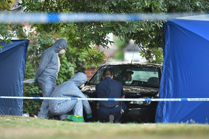 Forensic police officers examine a car at the scene in Lennard Road.