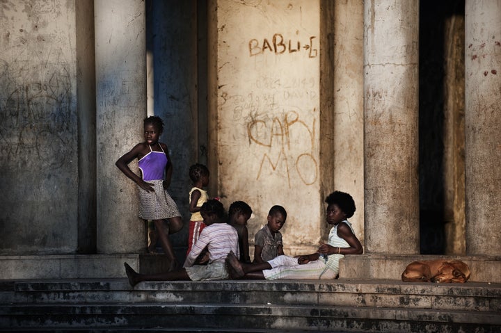 Mozambican children from Beira enjoy the sunset as they sit on the main entrance of the Grand hotel Beira on November 2, 2010 in Beira, Mozambique. The Grande Hotel Beira was a luxury hotel in Beira, Mozambique that was open from 1952 to 1963. It continued to be used during the 1960s as a conference center and swimming pool. During the Mozambican Civil War (1977-1992) it became a refugee camp. Today the former hotel is occupied by approximately 1,000 squatters who live in substandard conditions.