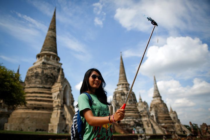 A tourist snaps a picture of herself with a selfie stick at Wat Phra Sri Sanphet, a temple in the ancient city of Ayutthaya, Thailand.