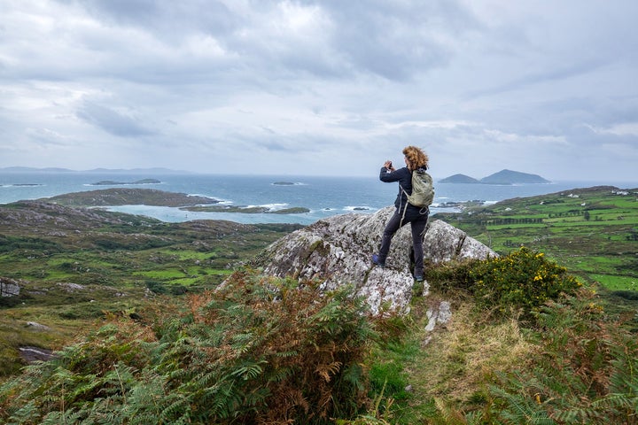 A woman snaps a photograph while hiking in the Beara Peninsula, Ireland.