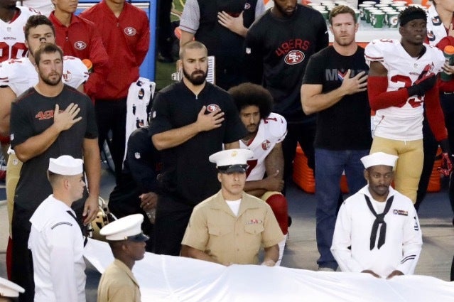 Colin Kaepernick (middle) kneels alone during the US national anthem.