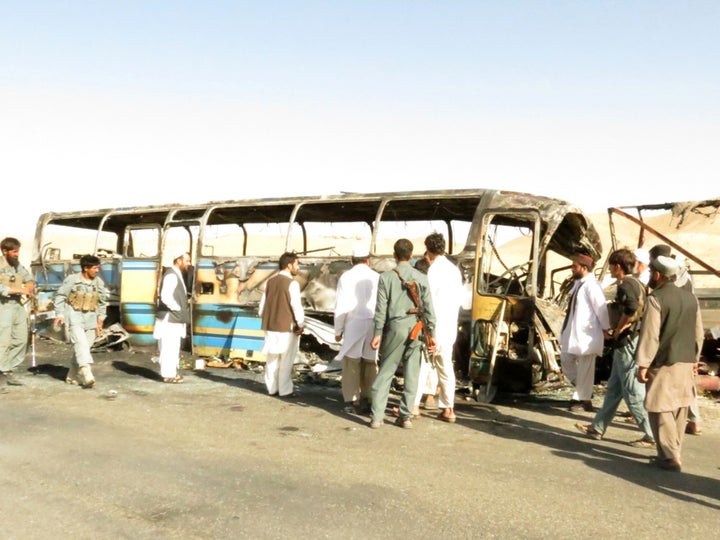 Security forces and civilians inspect the wreckage of a damaged bus after it collided with a lorry in Zabul, Afghanistan on S
