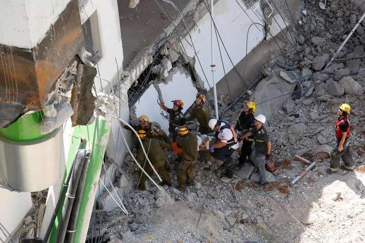 Israeli medics and emergency units carry a wounded person away on a stretcher from a construction site after an underground c