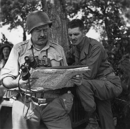 Ernest Hemingway looking at a map with a soldier during World War II, circa 1944.