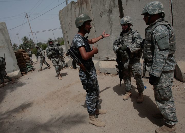 Lt. Col. Jim Crider of 1st Squad, 4th Cavalry Regiment of the 1st Infantry Division (C) and his interpreter (R) talk to an Iraqi police member about a recent insurgent attack in the tense Dora neighborhood June 20, 2007 in Baghdad, Iraq.