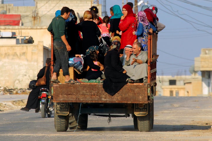 Civilians sit on a pick-up truck with their belongings in Taybat al Imam town after rebel fighters from the hardline jihadist