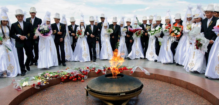 Kyrgyz brides and grooms lay flowers at the Eternal Flame before a mass wedding ceremony May 7, 2011. Some estimates say up to half of marriages in Kyrgyzstan are results of bride kidnapping with a third of those nonconsensual.