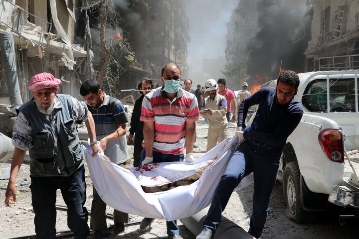 Syrians carry the body of a man after a helicopter belonging to the Syrian army carried out barrel bomb attacks on the Bayan hospital and a bazaar in Aleppo, Syria, on June 8.