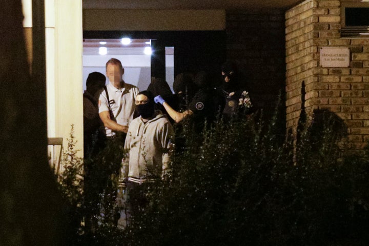 Police take a hooded woman, center, out of a building in Boussy-Saint-Antoine south of Paris on Thursday night.