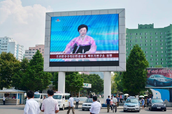 North Koreans walk past near a huge screen broadcasting the government's announcement on North Korea's fifth nuclear test in Pyongyang, North Korea, in this photo released by Kyodo September 9, 2016.