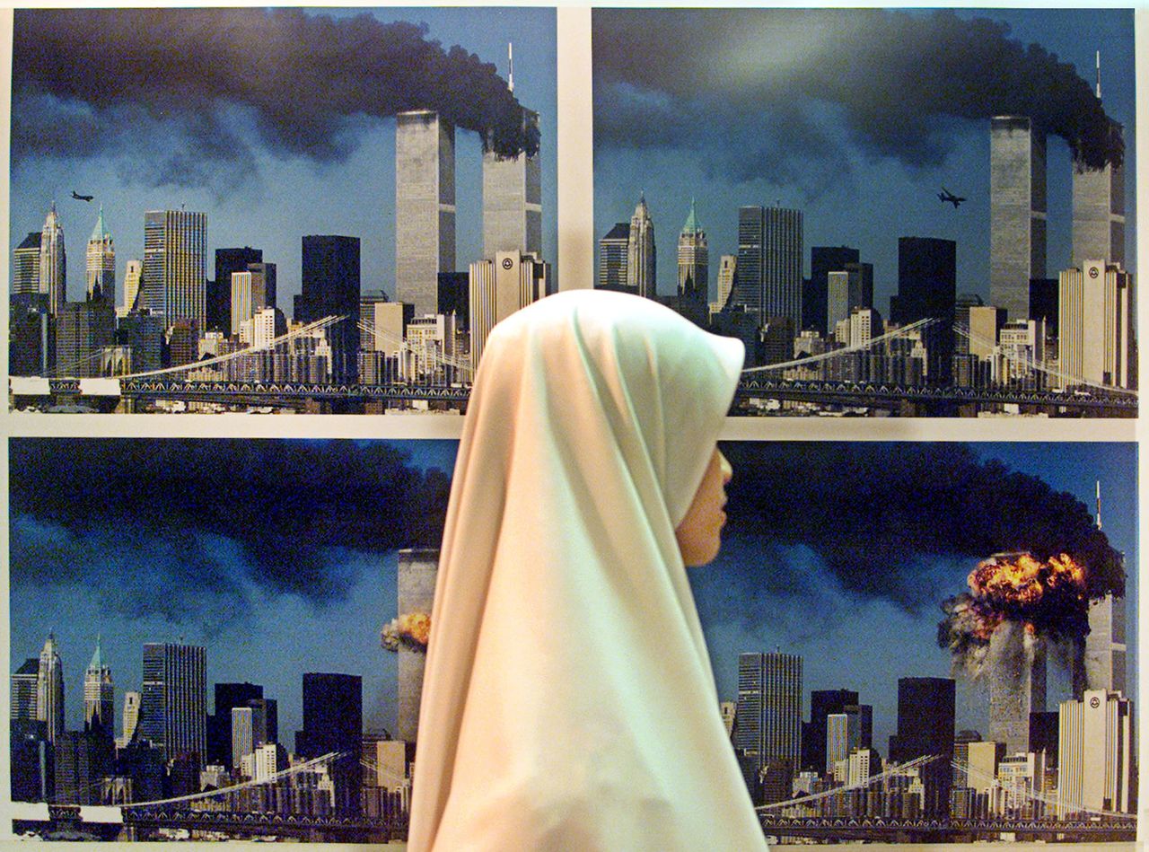 A Malaysian Muslim woman walks past a display of photos showing United Airlines flight 175 crashing into the World Trade Center South Tower at a gallery in Kuala Lumpur Sept. 25, 2002.