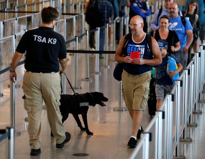 Travelers make their way past a TSA security officer and dog at Lindbergh Field airport in San Diego, California, U.S. July 1, 2016.