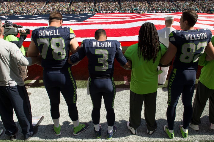 Seattle Seahawks join arms during the national anthem before their game against the Miami Dolphins.