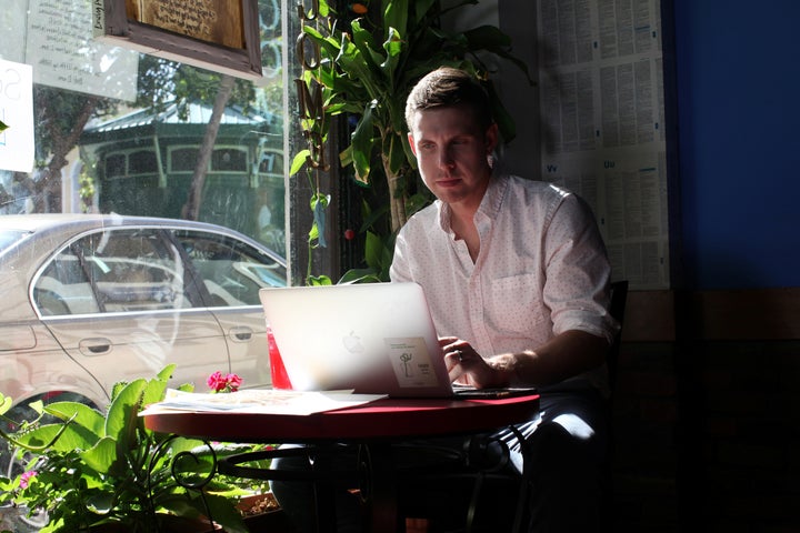 Reuters journalist Nick Brown works at his laptop at a cafe in San Juan, Puerto Rico, August 8, 2016. Picture taken August 8, 2016. (REUTERS/Alvin Baez)