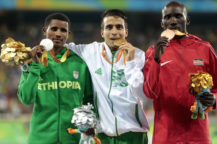 Silver medalist Tamiru Demisse, gold medalist Abdellatif Baka and bronze medalist Henry Kirwa celebrate on the podium at the medal ceremony for the Men's 1500m - T13 Final.