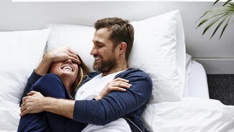 Young woman lying on mattress with man covering eyes of his girlfriend - Indoors