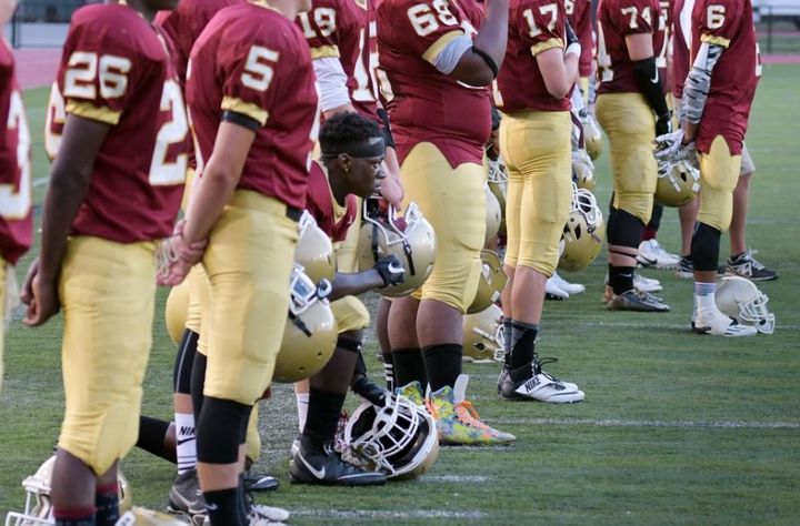 Doherty High School football player Michael Oppong on one knee during playing of the national anthem before the teams game against Leominster on Friday.