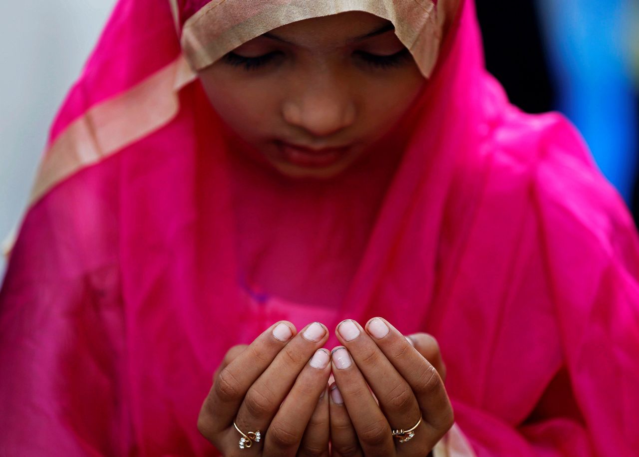 A girl offers Eid al-Adha prayers on a street outside a railway station in Mumbai, India.