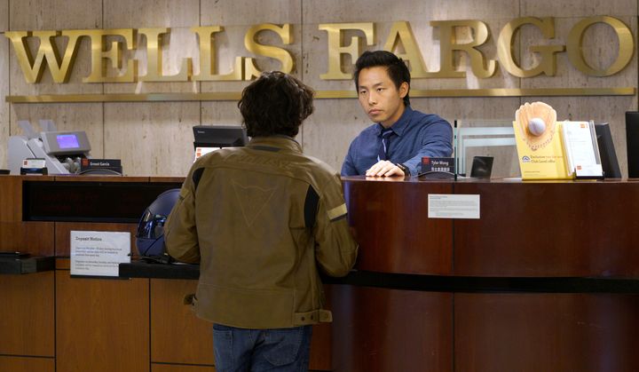 Bank Teller Tyler Wong talks to a customer at the Wells Fargo bank in Denver, Colorado, U.S. April 13, 2016.