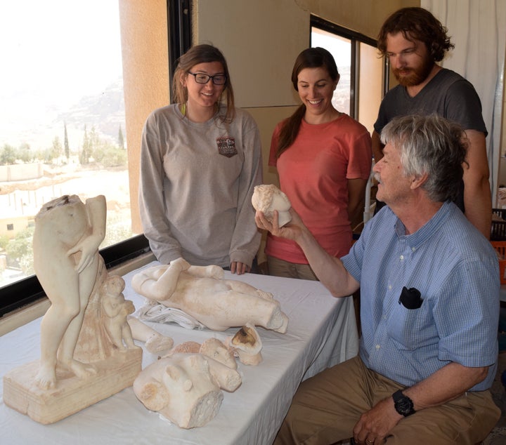 NC State Professor Tom Parker examines one of the statues alongside students who also took part in the dig 