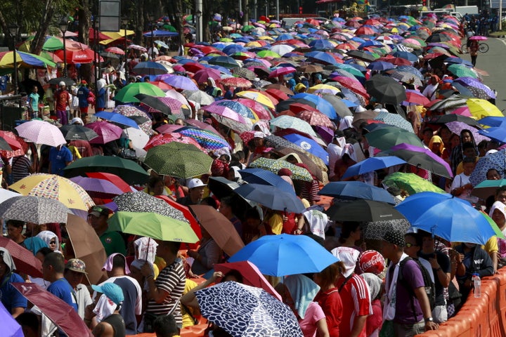 Devotees wait in line with umbrellas in the scorching heat for their turn to hold and kiss the foot of a Jesus of the Black Nazarene statue on the eve of the annual procession in Luneta Park in Manila on Jan. 8.