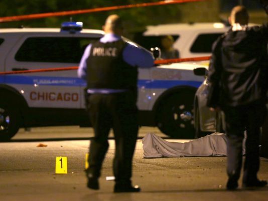 In this May 30, 2016, photo, police work the scene where a man was fatally shot in the chest in Chicago's Washington Park neighborhood.
