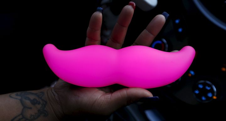 A Lyft driver holds a copy of the company's signature pink mustache logo. The ride-hailing service is partnering with Budweiser to offer subsidized late-night rides in a bid to combat drunk driving.