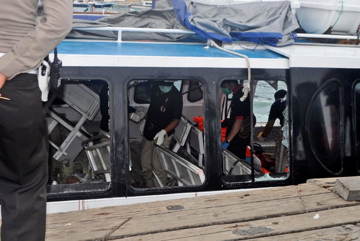 Police investigators examine the Gili Cat 2 boat following an explosion while it was enroute to nearby island of Lombok