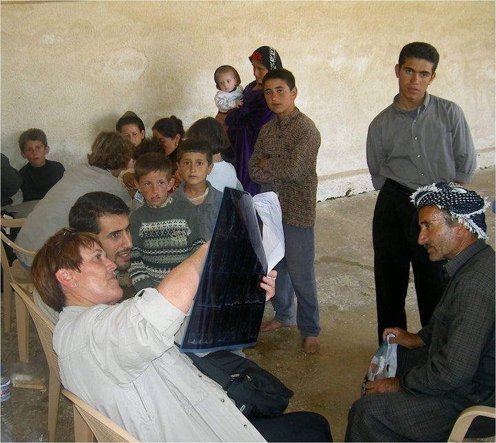 Mary Burry surrounded by local villagers, reviews a patient X-Ray inside the Iraqi village’s mosque.