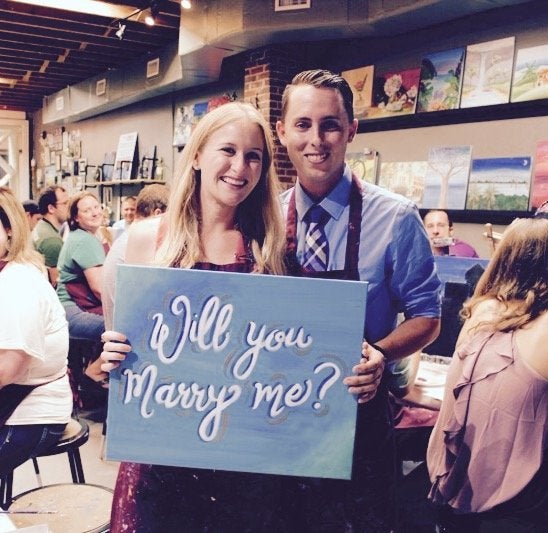 The happy couple posing with the "Will you marry me?" painting. 