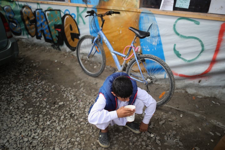 A young boy drinks tea outside the Jungle Books Cafe in the Jungle migrant camp on September 6, 2016 in Calais, France