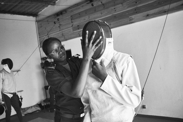 Prison guard Fatoumata Sy assists a boy with his mask, part of a group of minors incarcerated at a nearby prison participating in a fencing session.