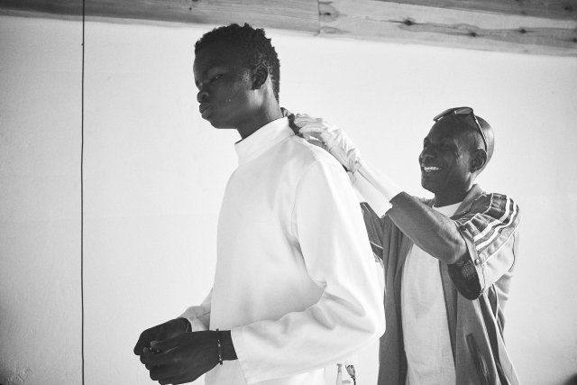 Daouda, 17, dresses in preparation for a fencing match.