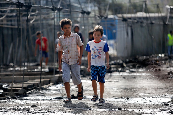 Children walk past the charred remains of tents on Sept. 20, 2016, after a fire ripped through Moria camp.