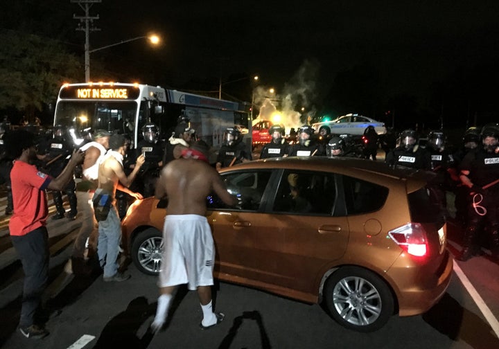 Police officers wearing riot gear block a road during protests after the shooting 