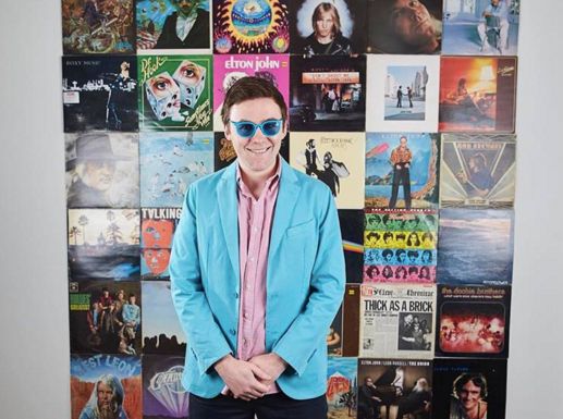 Tom Cridland, a music enthusiast, in front of a wall of vinyl records.