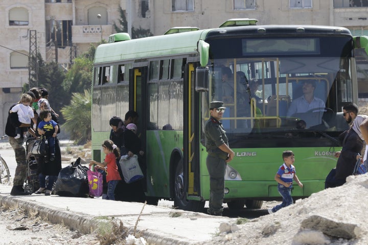 Families of opposition fighters board a bus at a Syrian army checkpoint on the edge of the rebel-held Waer neighbourhood in t
