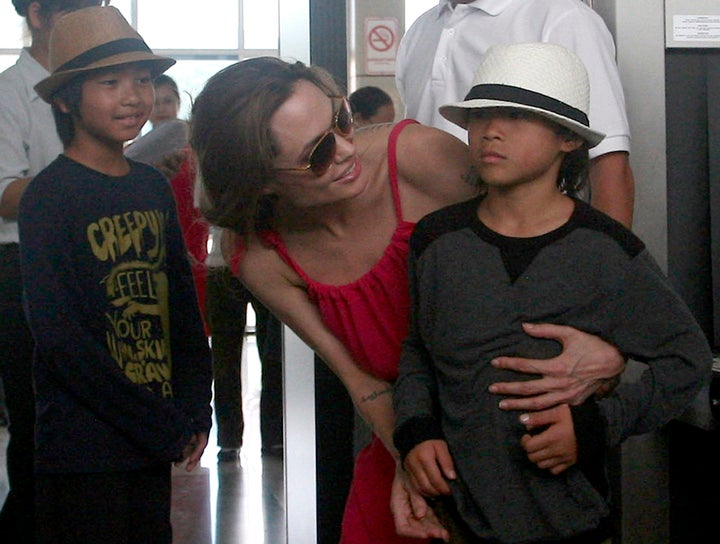 Hollywood actress Angelina Jolie (C) chats with her adopted son Pax Thien, from Vietnam, next to Maddox (L), from Cambodia, at a security checkpoint before leaving Con Dao island, off Vietnam's southern coast, Nov. 16, 2011.