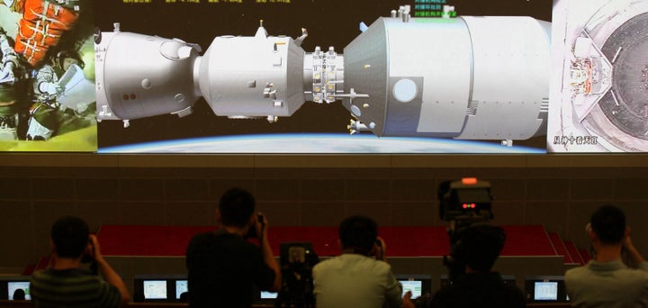 Scientists look at the screen showing the Shenzhou X manned spacecraft conducting docking with the orbiting Tiangong-1 space module at Beijing Aerospace Control Center on June 13, 2013.