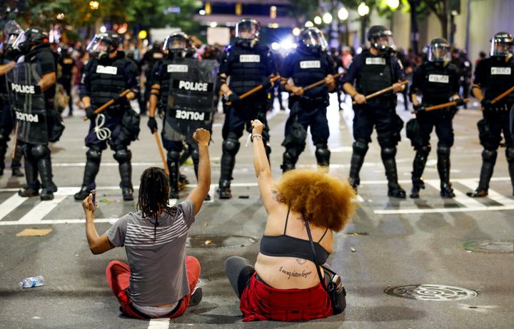 Protesters sit in front of police in riot gear during the Charlotte uprising.
