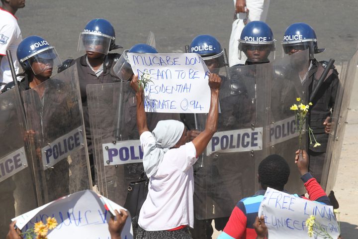A woman holds a banner with a message directed at President Robert Mugabe during a protest against the introduction of bond notes by the Reserve Bank of Zimbabwe, in Harare, Aug. 17, 2016. As Zimbabweans continue to take to the streets to call for reform, female demonstrators have been reporting abuse by police.