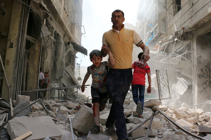 A Syrian man evacuates an area following a reported airstrike on April 22, 2016 in the rebel-held neighborhood of Hayy Aqyul in Aleppo.