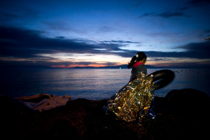 A Syrian girl holds on to a rubber float during sunrise after arriving on an inflatable boat with other refugees, crossing the sea from Turkey to Lesbos, Greece, on March 9, 2016.