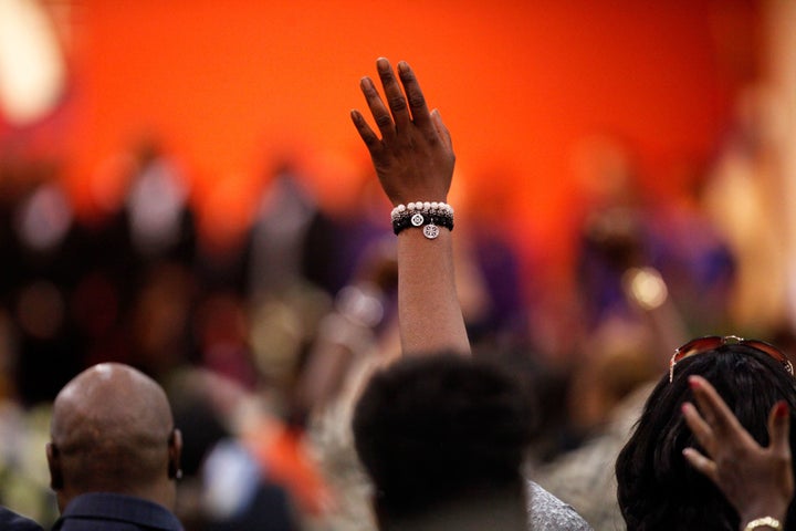 An attendee holds up their hand during the funeral.