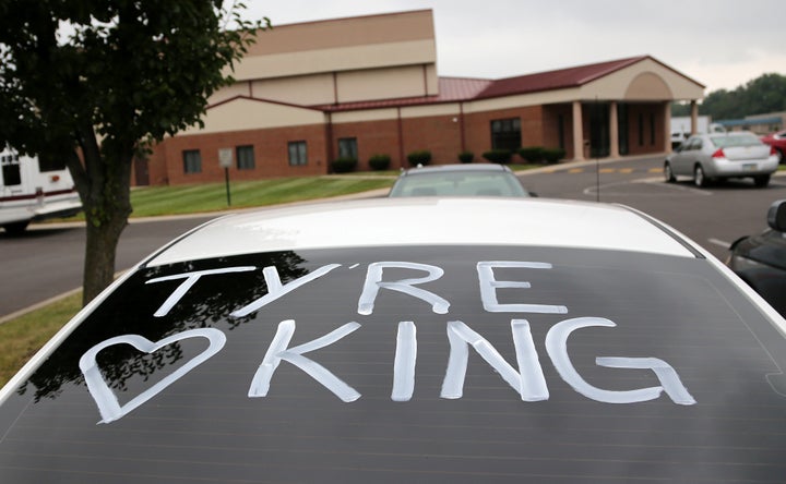 A car with its rear window painted is parked outside the First Church of God during the funeral of Tyre King.