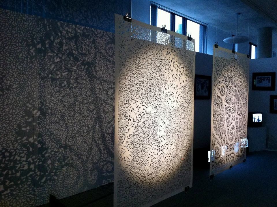 These paper sheets, seen speckled with cutout leaves, resemble intricate tapestries that can be placed before a window to highlight its complex design.